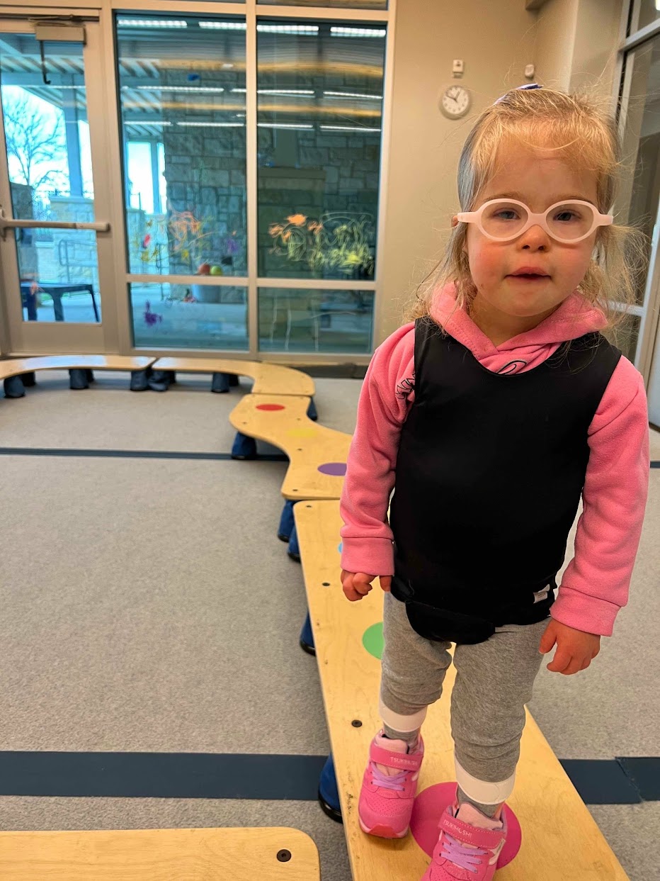 Young girl standing on a balance beam during physical therapy at The Rise School